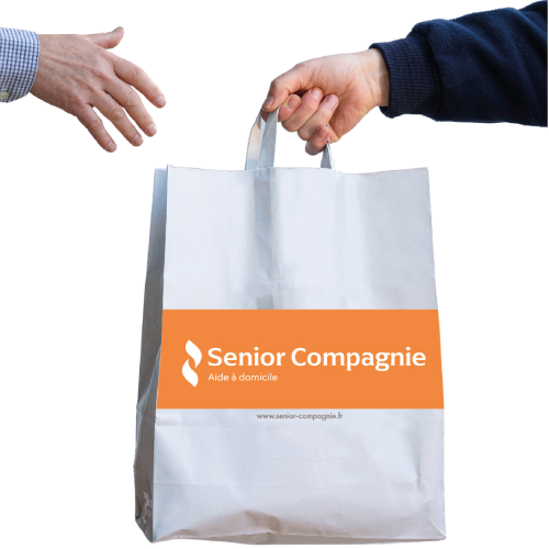 Une main tend un sac en papier Senior Compagnie à une autre main.